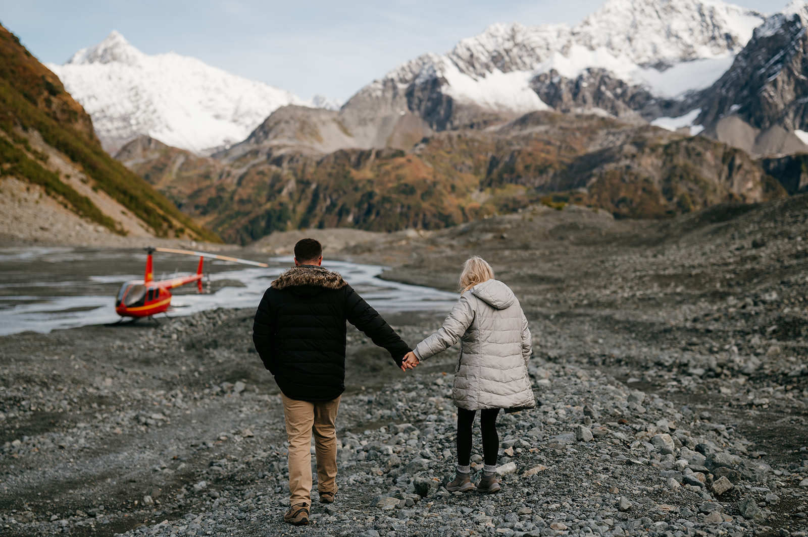 Couple walks back to helicopter after exploring glacier